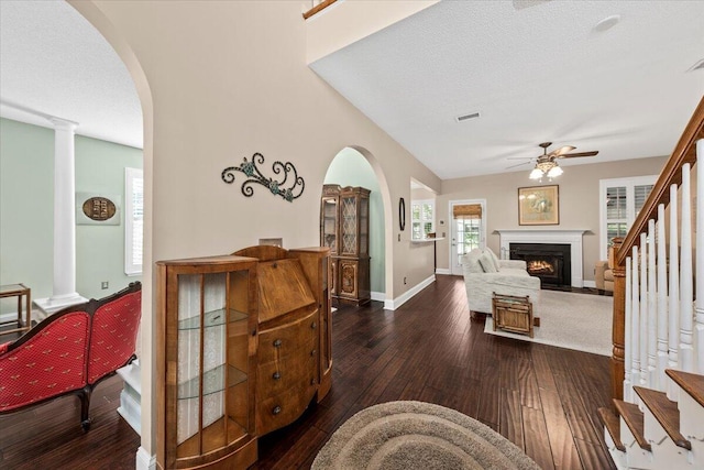 living room with a textured ceiling, ceiling fan, and dark hardwood / wood-style floors