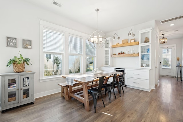 dining area with hardwood / wood-style flooring, beverage cooler, and an inviting chandelier