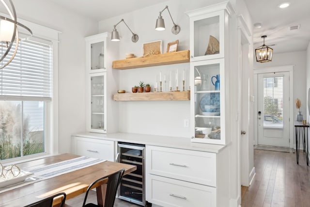 bar featuring wine cooler, white cabinetry, a chandelier, pendant lighting, and hardwood / wood-style floors