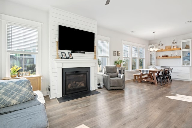 living room featuring hardwood / wood-style flooring, a large fireplace, and ceiling fan with notable chandelier