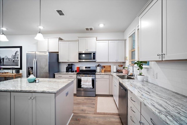 kitchen with sink, white cabinetry, a center island, pendant lighting, and stainless steel appliances