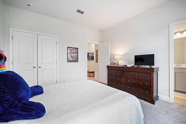 carpeted bedroom featuring ensuite bath, sink, and a closet