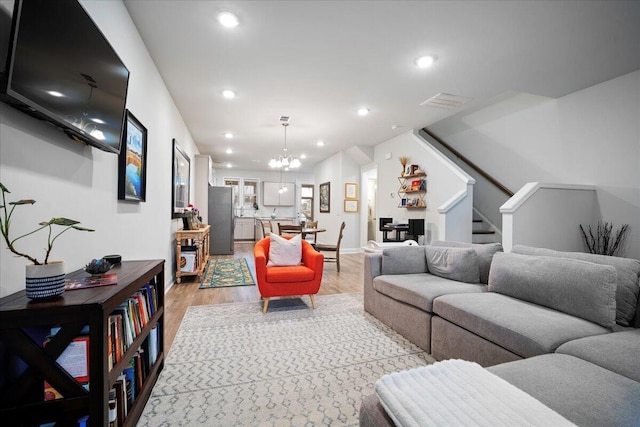 living room with light hardwood / wood-style floors and a notable chandelier