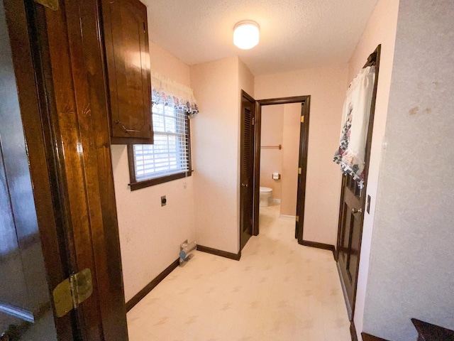 laundry area with a textured ceiling, electric dryer hookup, and baseboards