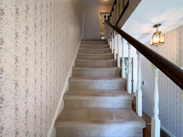 staircase featuring wainscoting and wallpapered walls