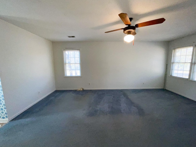 unfurnished room featuring dark colored carpet, visible vents, and baseboards