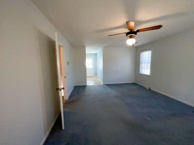 carpeted spare room featuring ceiling fan and baseboards