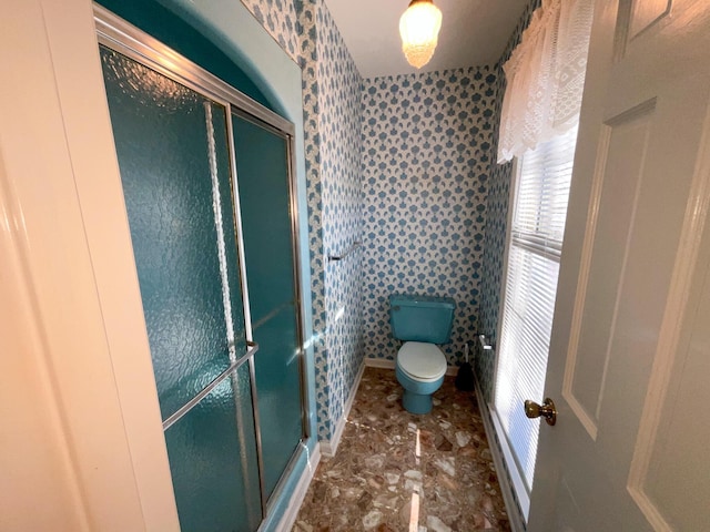 full bathroom featuring toilet, wallpapered walls, a shower stall, and baseboards