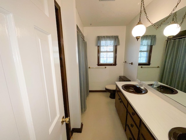 bathroom with baseboards, vanity, and toilet