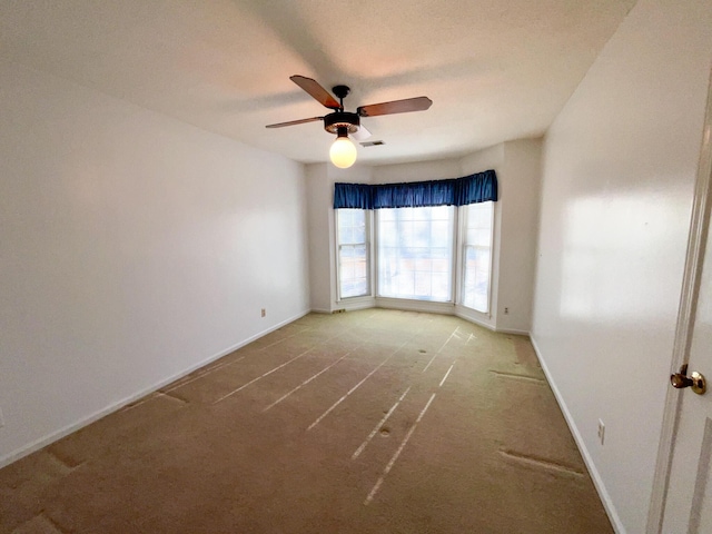 empty room with a ceiling fan, visible vents, and baseboards