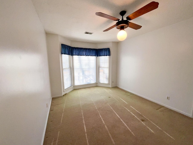 unfurnished room featuring carpet, baseboards, visible vents, and ceiling fan