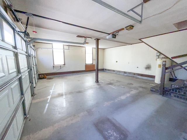 garage featuring a garage door opener, water heater, and baseboards