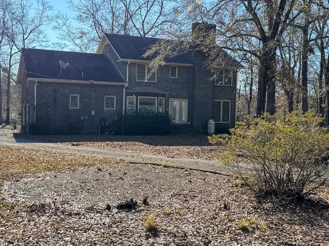 exterior space with a chimney, french doors, and brick siding