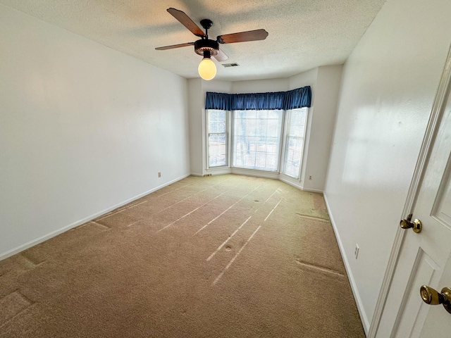 empty room with light colored carpet, visible vents, a textured ceiling, and baseboards