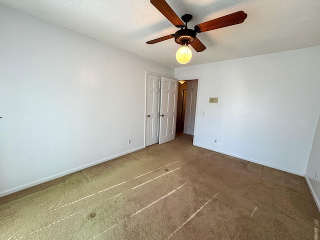 unfurnished bedroom with carpet flooring, ceiling fan, a textured ceiling, and baseboards