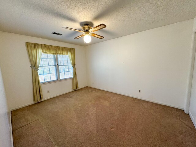 empty room featuring a ceiling fan, light colored carpet, visible vents, and baseboards