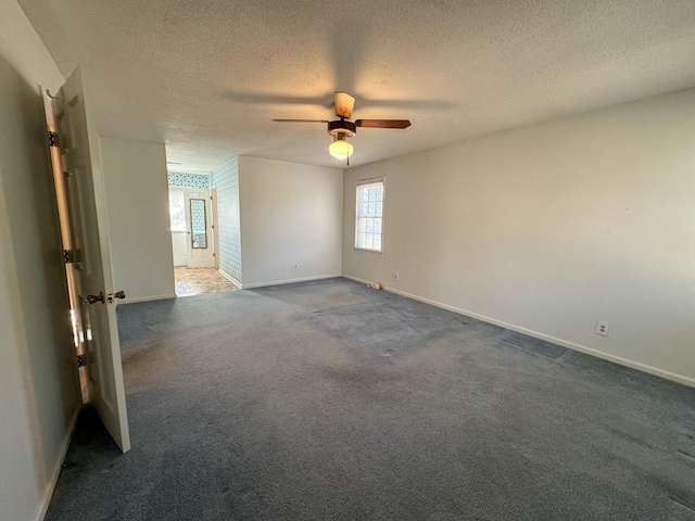 unfurnished room featuring baseboards, dark carpet, ceiling fan, and a textured ceiling