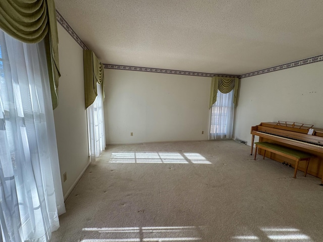 unfurnished room with carpet, visible vents, and a textured ceiling