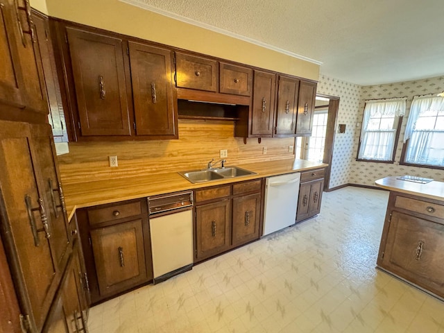 kitchen with light floors, white dishwasher, a sink, and wallpapered walls