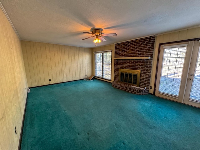 unfurnished living room with a textured ceiling, a brick fireplace, carpet flooring, and a ceiling fan