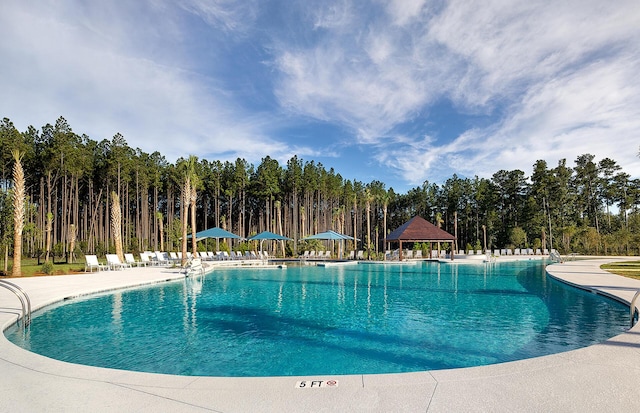 community pool featuring a forest view, a gazebo, and a patio