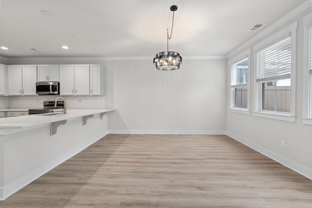 5133 Park Creek Ave, North Charleston, SC 29418 - kitchen featuring stainless steel appliances, light countertops, ornamental molding, a kitchen breakfast bar, and tasteful backsplash