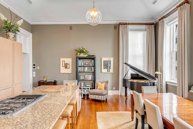 dining area with a chandelier, visible vents, crown molding, and light wood-style flooring