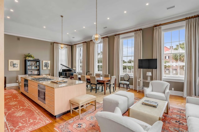 kitchen featuring visible vents, a center island, light countertops, crown molding, and pendant lighting