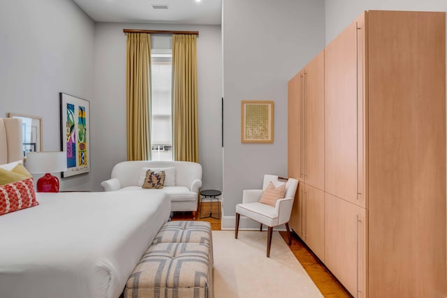 bedroom with light wood-style floors, visible vents, and baseboards