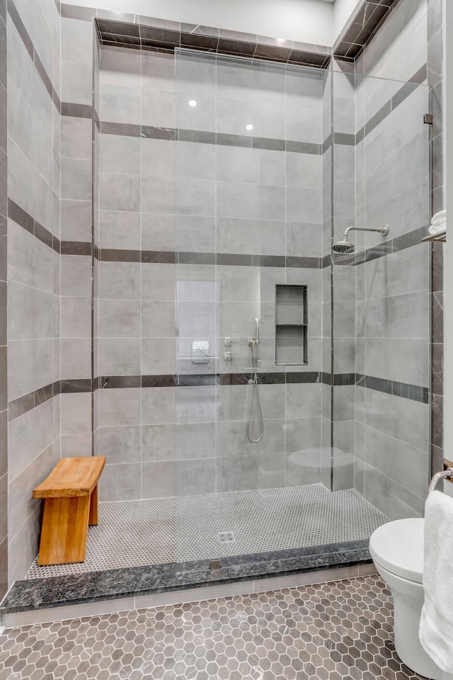 full bathroom with a tile shower and toilet