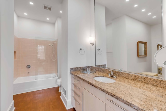 bathroom featuring visible vents, toilet, vanity, wood finished floors, and  shower combination