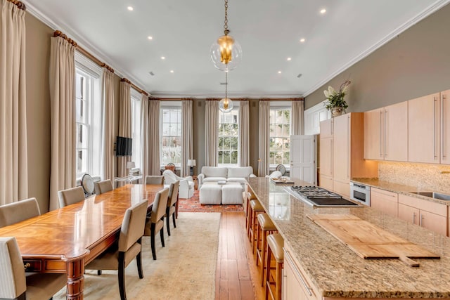 kitchen with open floor plan, hanging light fixtures, ornamental molding, light stone countertops, and stainless steel gas stovetop