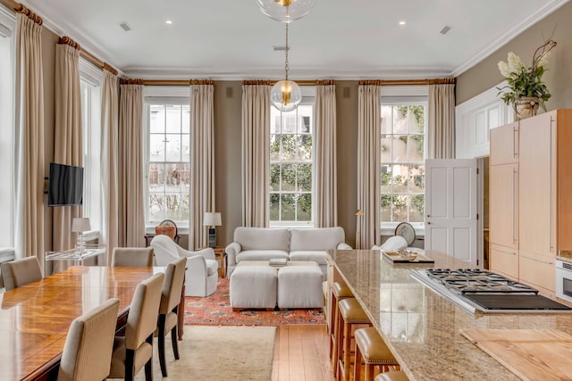 dining space with light wood-type flooring, visible vents, and crown molding