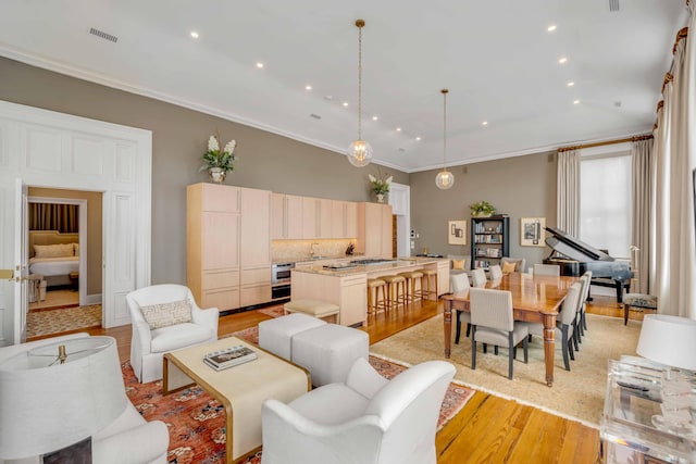 living room with light wood-style floors, recessed lighting, visible vents, and ornamental molding