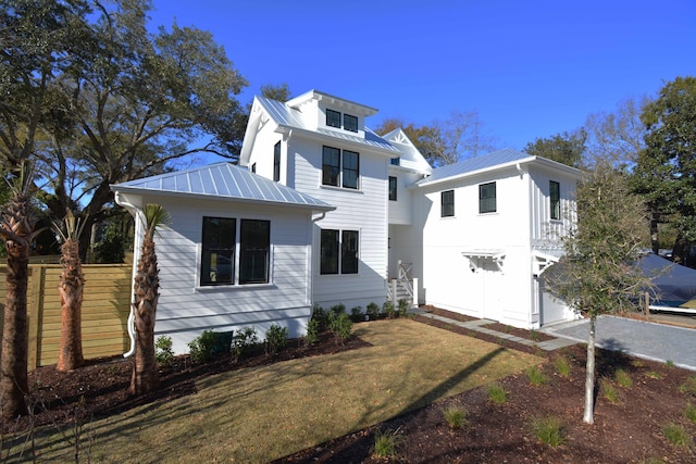 view of front of home featuring a standing seam roof, metal roof, a garage, and a front yard