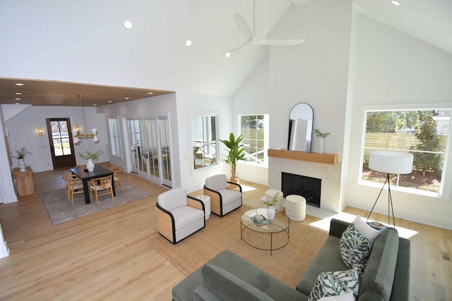 living area with recessed lighting, a fireplace, light wood-type flooring, and high vaulted ceiling