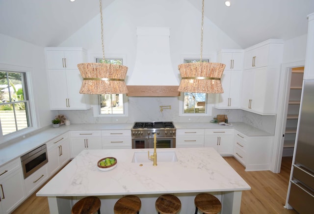 kitchen featuring custom range hood, appliances with stainless steel finishes, a breakfast bar area, and lofted ceiling