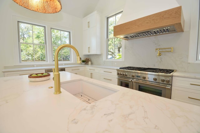 kitchen featuring range with two ovens, light stone counters, backsplash, and custom range hood