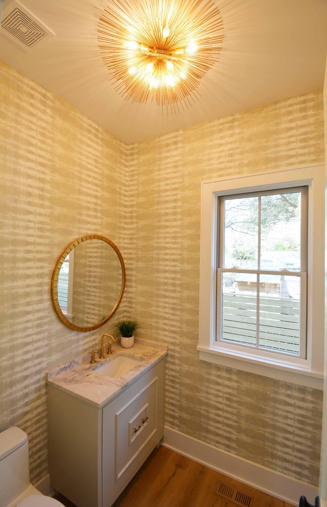 bathroom with vanity, toilet, wood finished floors, and visible vents