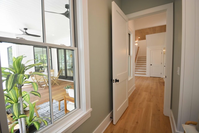 hall with light wood finished floors, stairs, and baseboards