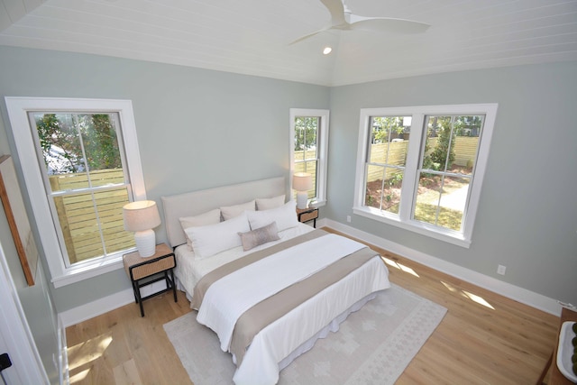 bedroom featuring baseboards, multiple windows, wood finished floors, and vaulted ceiling