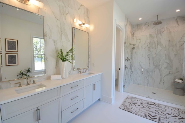 bathroom with toilet, a marble finish shower, and a sink