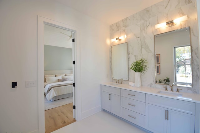 ensuite bathroom with ensuite bath, wood finished floors, double vanity, and a sink