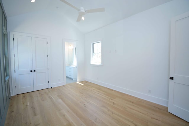 unfurnished bedroom featuring connected bathroom, baseboards, light wood-type flooring, and lofted ceiling