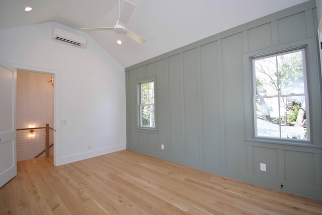 empty room featuring a wealth of natural light, a decorative wall, a wall mounted AC, and light wood-style floors