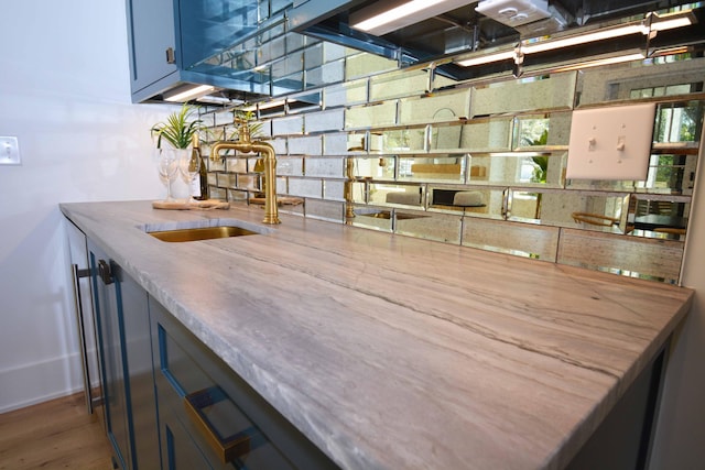 bar featuring wood finished floors, backsplash, wet bar, and a sink