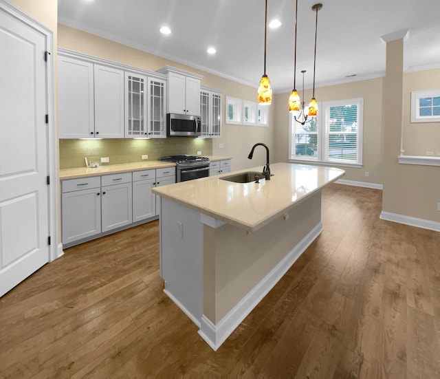 kitchen with white cabinets, hardwood / wood-style flooring, gas stove, a kitchen island with sink, and sink