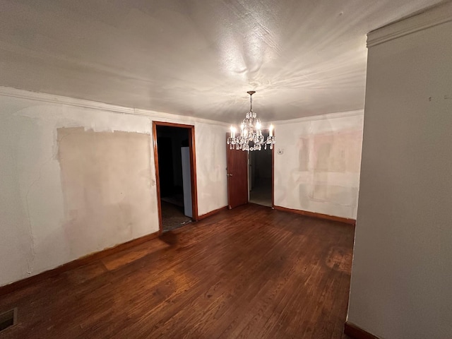 unfurnished room with crown molding, dark hardwood / wood-style floors, and an inviting chandelier