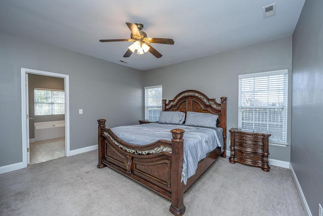 bedroom featuring light carpet, ensuite bathroom, and ceiling fan