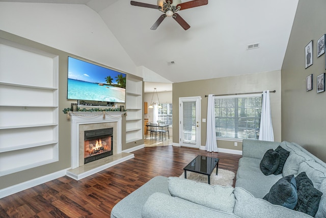 living room featuring built in shelves, dark hardwood / wood-style flooring, a premium fireplace, ceiling fan, and high vaulted ceiling